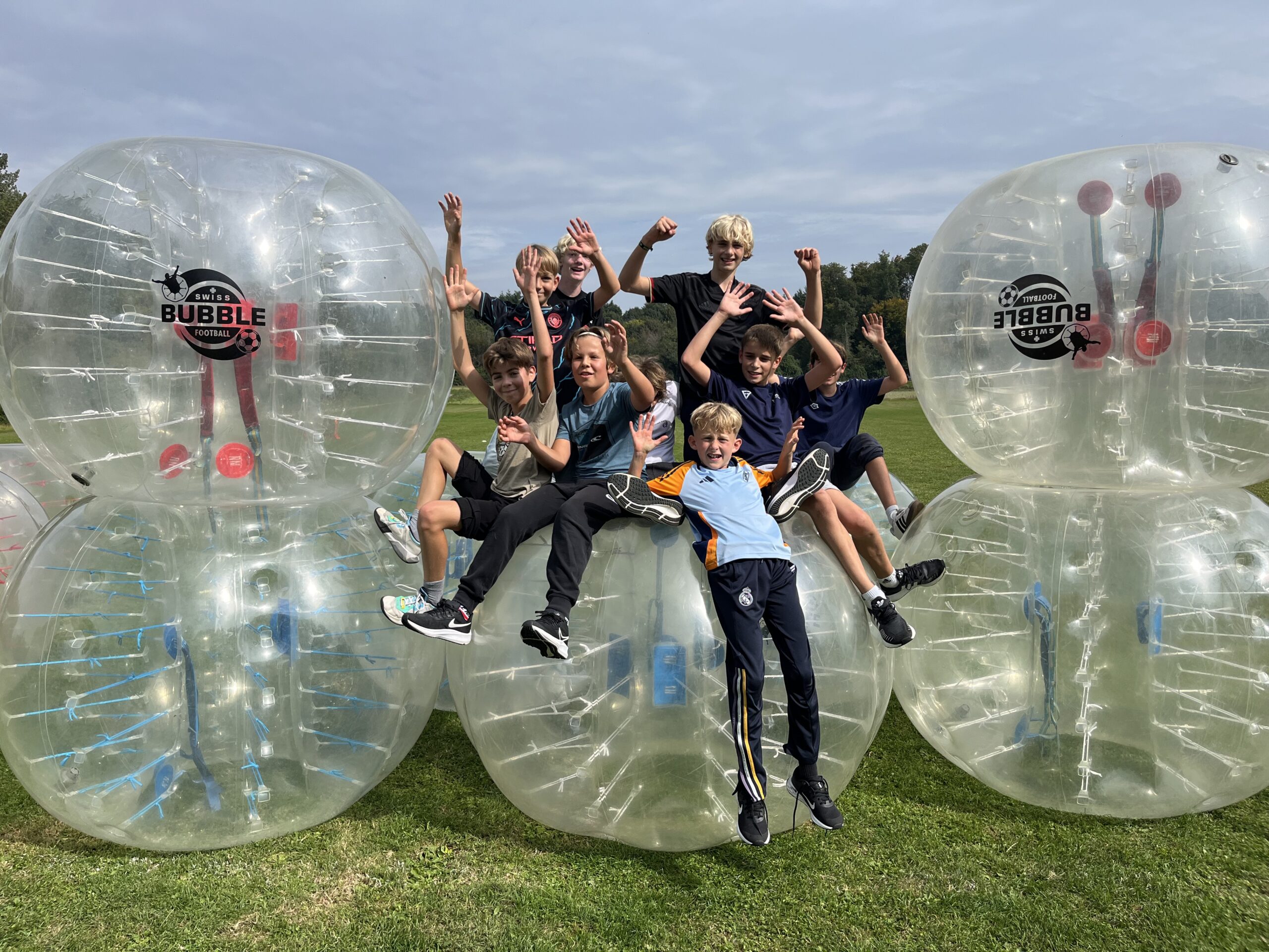 Jeunes joueurs de Bubble Foot qui célébrent une victoire en extérieur près du Lac Léman
